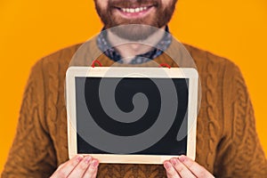 young caucasian man holding a small whiteboard in front of the camera