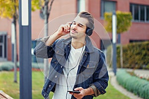 Young caucasian man listening music by headphones in park