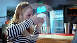 Young Caucasian man with long hair talking and gesturing sitting at bar counter in pub. Portrait of relaxed millennial