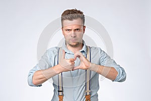 Young caucasian man making friendzone symbol, isolated on gray wall