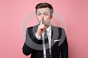 Young caucasian man making silence gesture asking to keep secret