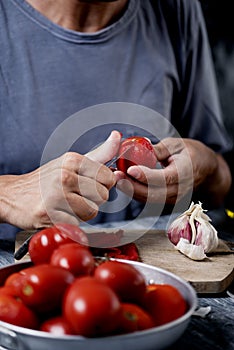 Young caucasian man peeling a scalded tomato
