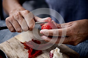 Young caucasian man peels a scalded tomato