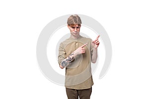 young caucasian man with red hair dressed in a khaki shirt and brown trousers points his hand to the side