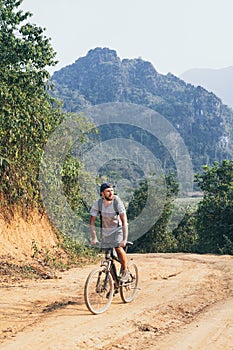 Young Caucasian man riding a mountain bicycle uphill in Muang Ngoi village, Laos