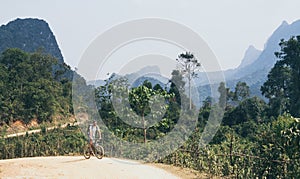 Young Caucasian man riding a mountain bicycle uphill in Muang Ngoi village, Laos