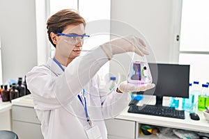 Young caucasian man scientist looking test tube at laboratory