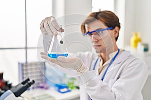 Young caucasian man scientist looking test tube at laboratory