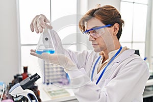 Young caucasian man scientist looking test tube at laboratory