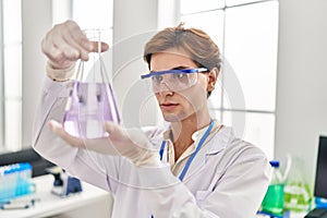 Young caucasian man scientist looking test tube at laboratory