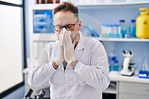 Young caucasian man scientist using napkin at laboratory