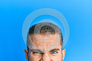 Young caucasian man showing head and half face sticking tongue out happy with funny expression