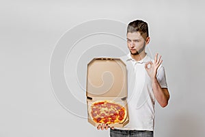 Young caucasian man shows that OK. On-line pizza delivery from restaurant. Safety delivery without coronavirus