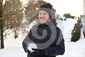 Young caucasian man with a snowball on his hands in a park during Filomena snowstorm in Madrid, Spain photo