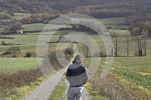 Young Caucasian man in sportswear walking along a path winding through green and yellow grasses.