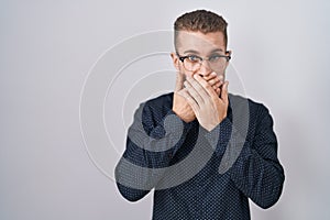 Young caucasian man standing over isolated background shocked covering mouth with hands for mistake