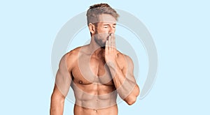 Young caucasian man standing shirtless bored yawning tired covering mouth with hand