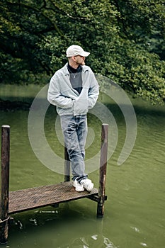 Young Caucasian man standing on a wooden dock.