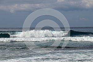 Young caucasian man surfs the ocean wave and makes a lot of splashes into the camera. Nyang Nyang Surf Spot in Bali, Indonesia.