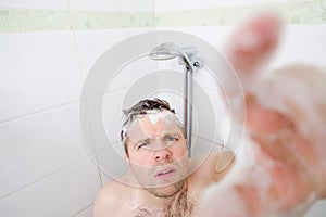 A young caucasian man takes a shower and notices a hidden camera.