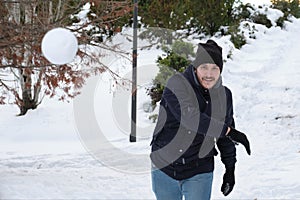 Young caucasian man throwing a snowball in a park during Filomena snowstorm in Madrid, Spain photo