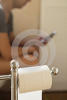 Young man using his smartphone in the toilet photo