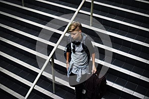 Young caucasian man waking down the stairs with luggage