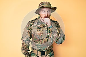 Young caucasian man wearing camouflage army uniform feeling unwell and coughing as symptom for cold or bronchitis