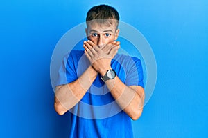 Young caucasian man wearing casual blue t shirt shocked covering mouth with hands for mistake