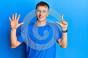 Young caucasian man wearing casual blue t shirt showing and pointing up with fingers number seven while smiling confident and