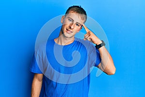 Young caucasian man wearing casual blue t shirt smiling pointing to head with one finger, great idea or thought, good memory