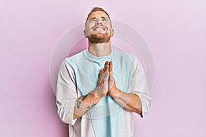 Young caucasian man wearing casual clothes begging and praying with hands together with hope expression on face very emotional and