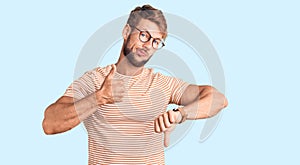 Young caucasian man wearing casual clothes and glasses doing thumbs up and down, disagreement and agreement expression
