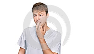 Young caucasian man wearing casual white t shirt bored yawning tired covering mouth with hand