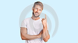 Young caucasian man wearing casual white tshirt with a big smile on face, pointing with hand and finger to the side looking at the