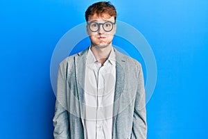 Young caucasian man wearing elegant clothes and glasses puffing cheeks with funny face