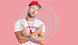 Young caucasian man wearing lifeguard t shirt holding whistle pointing to both sides with fingers, different direction disagree