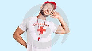 Young caucasian man wearing lifeguard t shirt holding whistle stretching back, tired and relaxed, sleepy and yawning for early