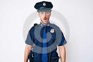 Young caucasian man wearing police uniform afraid and shocked with surprise and amazed expression, fear and excited face