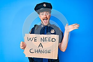 Young caucasian man wearing police uniform holding we need a change banner celebrating victory with happy smile and winner