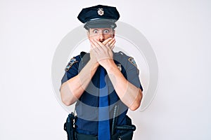 Young caucasian man wearing police uniform shocked covering mouth with hands for mistake