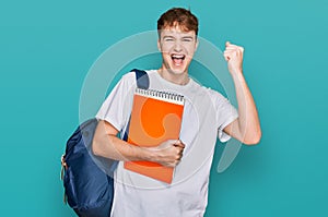 Young caucasian man wearing student backpack and holding books screaming proud, celebrating victory and success very excited with