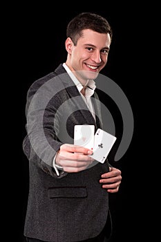 Young caucasian man wearing suit holding two aces in his hand on black background. Gambling concept. Casino