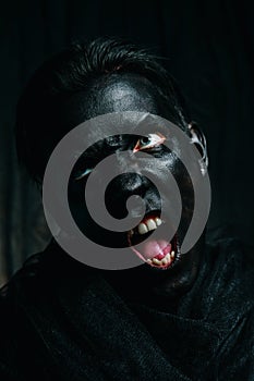 Young caucasian man with white skin painted his face and hands to black color and love it. close up halloween portrait.