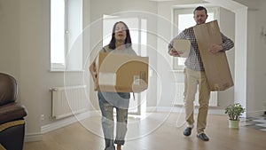 Young Caucasian man and woman entering their new house holding boxes with their belongings. Happy family moving into