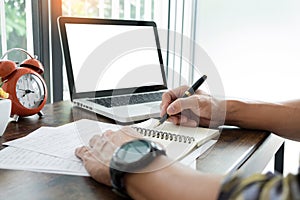 young caucasian man working at home planning work writing note on some project with his laptop on a desk, strartup business, e