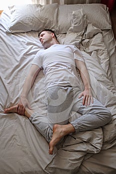 Young caucasian man working out at home at the bed doing Spinal Twist