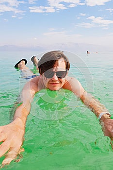 Young caucasian man about 29 years old is swimming when relaxing at the beach of the resort. Sea season summer. Close-up, vertical