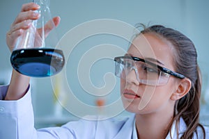 Young caucasian medical scientist wearing protective glasses looked at the test tube containing sample for viurs vaccination