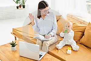 A young Caucasian mother with an infant works from home